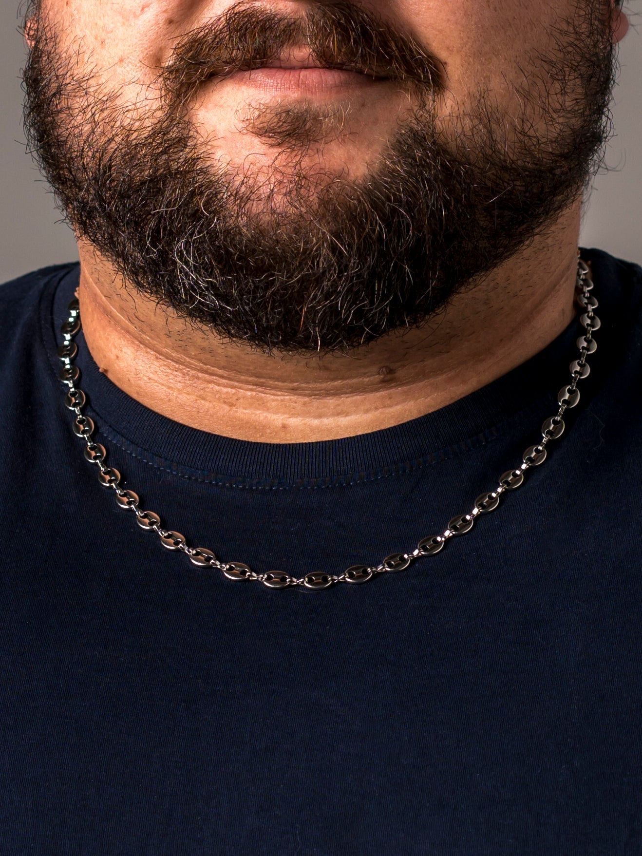 A man in a navy t-shirt wearing a silver Two Kxngs mariner chain