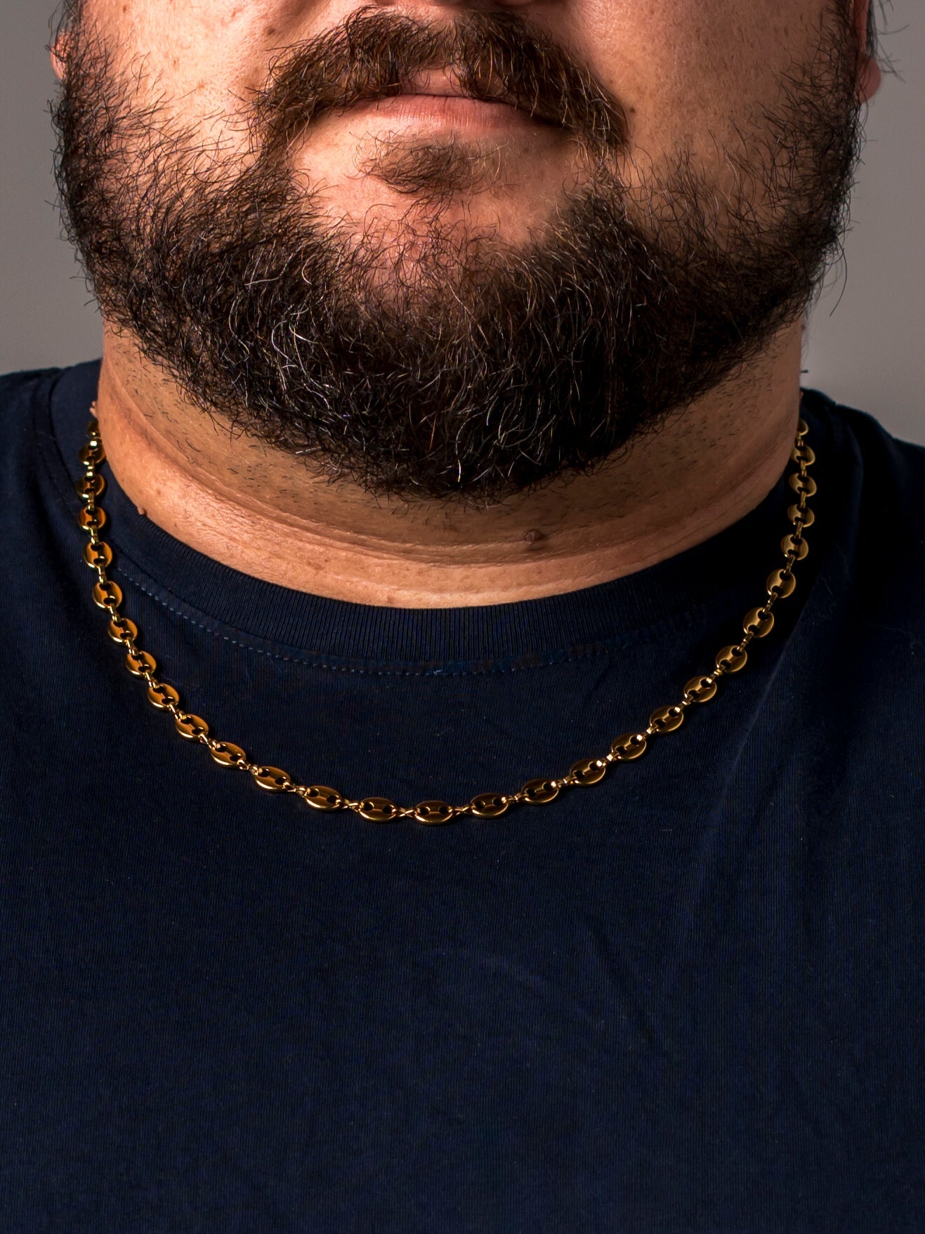 A man wearing a gold Two Kxngs mariner chain with a navy t-shirt