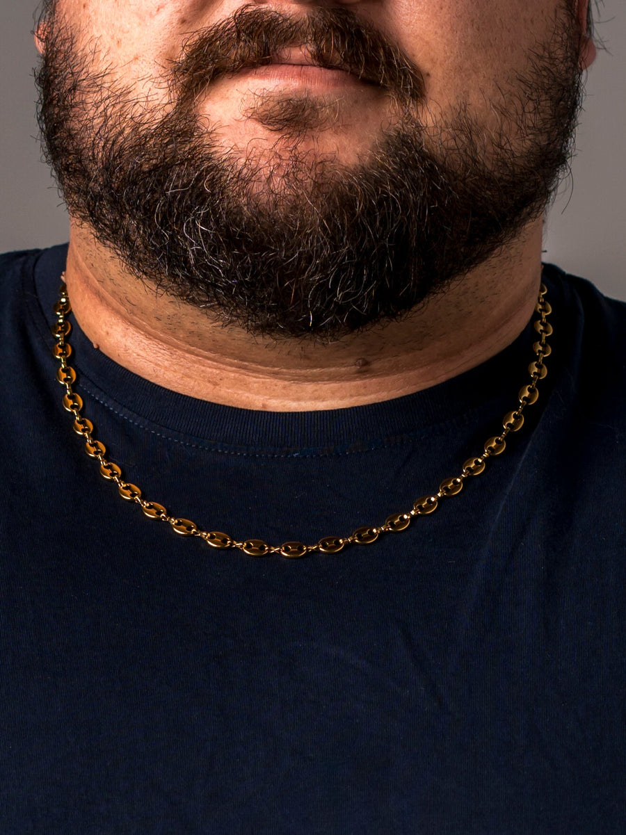 A man wearing a gold Two Kxngs mariner chain with a navy t-shirt