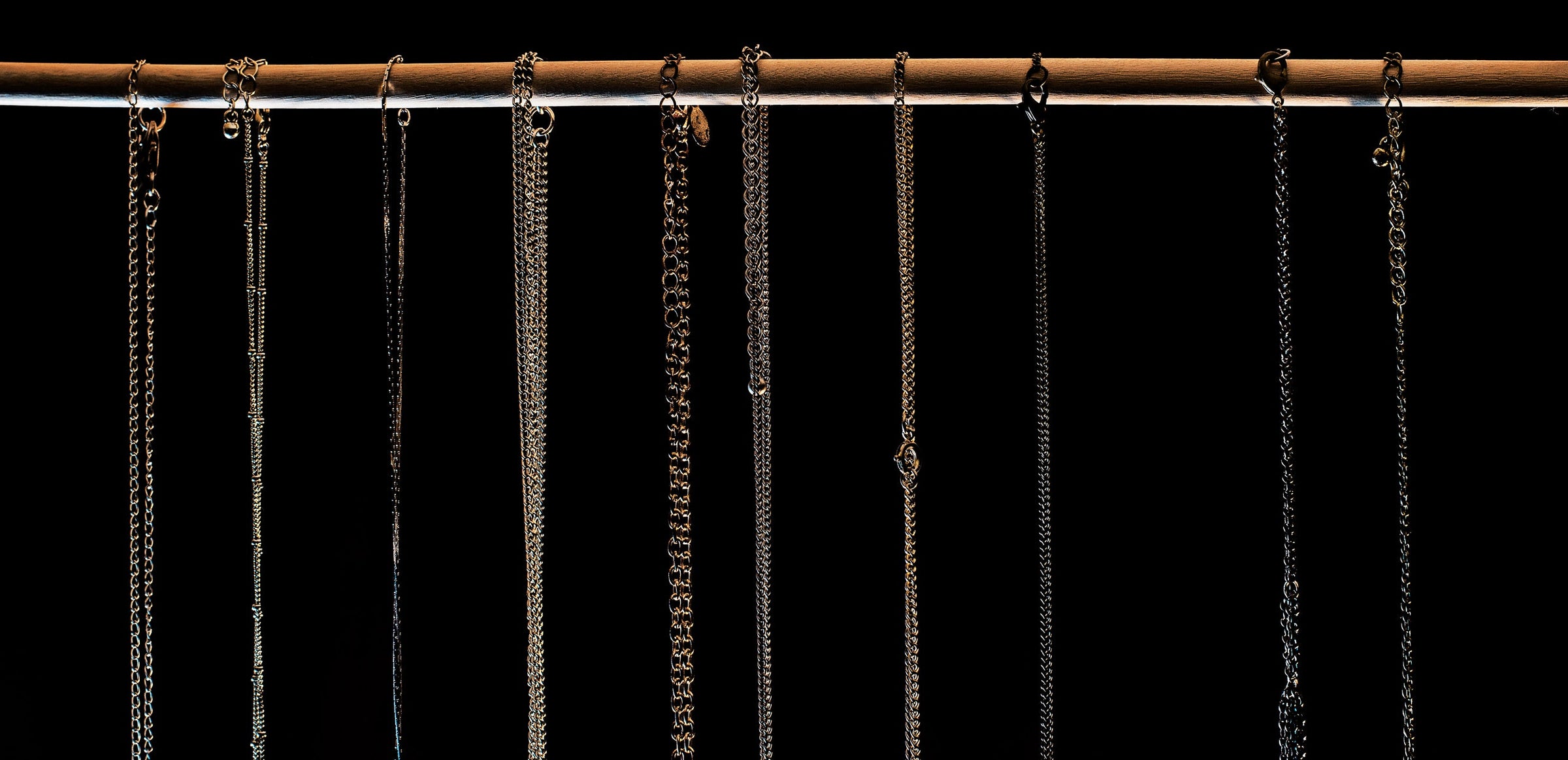 Two Kxngs chains in silver and gold hanging in a row against black