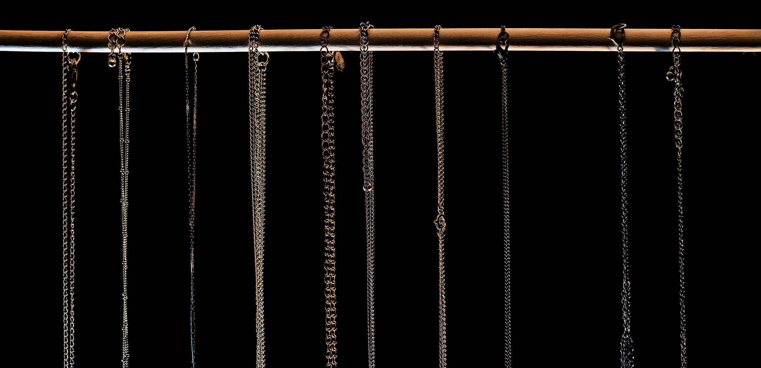 Two Kxngs chains in silver and gold hanging in a row against black